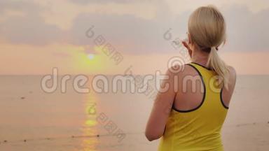 健身女是从瓶子里喝水。黎明时分，它矗立在海边一个风景如画的地方。清洁水和